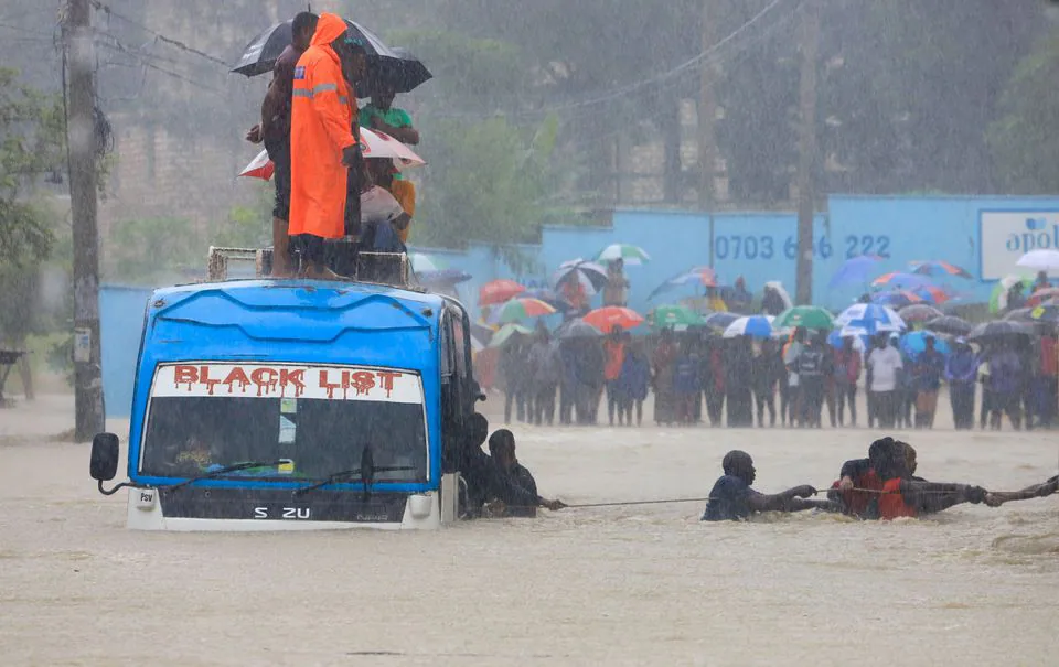 Bus passengers in Kenyan coastal city cling on rope to wade through chest-high rain water